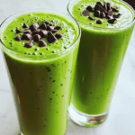 To make a tasty Mint Chocolate Chip Smoothie, gather these ingredients: - 1 cup unsweetened almond milk (or your preferred milk) - 1 ripe banana - 1 cup fresh spinach (for a nutrient boost) - 1 tablespoon cocoa powder - 1 tablespoon maple syrup (adjust to taste) - 1 teaspoon peppermint extract - 1/2 cup Greek yogurt (for creaminess) - 1/4 cup dark chocolate chips (plus extra for garnish) - Handful of ice cubes These ingredients blend together to create a refreshing drink that is full of flavor. Each serving of this smoothie has: - Calories: 250 - Protein: 10g - Carbohydrates: 40g - Fiber: 5g - Sugar: 15g - Fat: 6g This drink is not just tasty; it also packs in some good nutrients. The spinach adds vitamins, while the Greek yogurt gives you protein. You can easily swap some ingredients if you want. Here are some ideas: - Milk: Use coconut milk or oat milk for a different taste. - Banana: Try avocado for creaminess without the banana flavor. - Spinach: Kale works well too if you prefer that. - Maple Syrup: Honey or agave syrup can replace maple syrup. - Greek Yogurt: Use non-dairy yogurt for a dairy-free option. - Dark Chocolate Chips: You can use milk chocolate chips for a sweeter twist. These substitutions keep the smoothie delicious while meeting your taste or dietary needs. For the full recipe, check the original instructions above. Making a Mint Chocolate Chip Smoothie is fun and easy. First, gather your ingredients. You need almond milk, a ripe banana, fresh spinach, cocoa powder, maple syrup, peppermint extract, Greek yogurt, dark chocolate chips, and ice cubes. 1. In your blender, add 1 cup of almond milk. 2. Next, add 1 ripe banana. 3. Toss in 1 cup of fresh spinach for extra nutrients. 4. Add 1 tablespoon of cocoa powder and 1 tablespoon of maple syrup. 5. Then, pour in 1 teaspoon of peppermint extract. Blend these on high until the mix is smooth and creamy. 6. Now, add 1/2 cup of Greek yogurt and 1/4 cup of dark chocolate chips. 7. Toss in a handful of ice cubes. Blend again until everything is well mixed and cold. 8. Taste your smoothie. If you want it sweeter, add more maple syrup. If you like more mint, add extra peppermint extract. Pour the smoothie into two tall glasses and sprinkle some chocolate chips on top. Enjoy your refreshing drink! To get the best blend, start with the liquids at the bottom. This helps the blades move freely. Cut your banana into smaller pieces for easier blending. If your blender struggles, stop and stir the mix. You can also add more almond milk if it feels too thick. For an extra creamy texture, use chilled ingredients. Serve your Mint Chocolate Chip Smoothie right away. It tastes best when cold. You can pair it with a light snack, like fruit or yogurt. If you want a fun twist, add a dollop of whipped cream on top. For a special touch, try serving it in a fancy glass. This Mint Chocolate Chip Smoothie is perfect for breakfast or a quick treat. Check out the Full Recipe for more details! To get a super creamy texture, use Greek yogurt. It adds thickness and protein. I love adding a ripe banana, as it makes the smoothie creamy, too. For an even richer taste, try using full-fat coconut milk instead of almond milk. You can blend everything together until smooth. Taste your smoothie before serving. If you want it sweeter, add more maple syrup. Start with a small amount, then blend and taste again. For more mint flavor, add a little peppermint extract. Just be careful because it can be very strong. A drop or two goes a long way! You can boost nutrition by adding fresh spinach. It’s a great source of vitamins. You won’t even taste it! You can also toss in chia seeds or ground flaxseed for extra fiber and omega-3s. These tiny seeds pack a big punch. For a protein boost, add more Greek yogurt or protein powder. These tips will help you create a Mint Chocolate Chip Smoothie that is both tasty and healthy. For the full recipe, check out the details above! {{image_2}} You can easily make this smoothie dairy-free. Swap the Greek yogurt for a dairy-free version, like coconut yogurt. Use almond milk or oat milk instead of regular milk. These changes keep the taste creamy and delicious. Both options work well with the mint and chocolate flavors. Want to mix it up? You can add fruits! Try adding a half cup of berries like strawberries or raspberries. These fruits add natural sweetness and extra color. You can also include a few slices of avocado for creaminess. If you like a tropical twist, add a small piece of pineapple. Each fruit gives a new flavor to your smoothie. If you want to make it lighter, use less maple syrup. You can also skip the chocolate chips or use a smaller amount. Consider adding more spinach for volume without extra calories. This keeps your smoothie tasty and refreshing. You can enjoy a filling drink while staying on track with your goals. For the full recipe, check out the Mint Chocolate Chip Smoothie section above. To keep your mint chocolate chip smoothie fresh, store it in an airtight container. Use a glass jar or a plastic container with a tight lid. This helps to keep the flavor and nutrients intact. You can keep it in the fridge for up to 24 hours. After that, it may lose some freshness. If you want to save some for later, you can freeze the smoothie. Pour it into ice cube trays or freezer-safe bags. This way, you can make smoothie pops or blend it later without waste. Just make sure to leave some space in the container, as liquids expand when frozen. It can last in the freezer for up to a month. To enjoy your frozen smoothie, you have two options. You can thaw it in the fridge overnight or blend it straight from the freezer. If you blend it from frozen, add a little almond milk to help it mix well. This keeps the texture creamy and smooth. Enjoy your mint chocolate chip smoothie at its best! Yes, you can use frozen fruits! Frozen bananas work great in this recipe. They make the smoothie cold and thick. Plus, they blend well with other ingredients. If you use frozen spinach, it saves you time. Just toss everything in the blender and blend until smooth. Yes, this smoothie is healthy! It has good nutrients from spinach and banana. The Greek yogurt adds protein, which helps keep you full. The cocoa powder gives you antioxidants, too. If you want to make it even healthier, you can add more spinach or use less sweetener. To make this smoothie vegan, simply replace Greek yogurt with a plant-based yogurt. You can also swap almond milk for any non-dairy milk you like. The maple syrup is already vegan, so you’re all set! This way, you keep it creamy and tasty without animal products. For the full recipe, check out the complete guide above. In this article, we covered how to make a tasty Mint Chocolate Chip Smoothie. We explored ingredients, nutritional facts, and easy substitutions. You learned step-by-step instructions, helpful tips, and even fun variations. Remember, you can store your smoothie and freeze it for later. With these ideas, you can make a delicious drink that suits your taste. Enjoy experimenting with flavors and sharing with friends or family! Your perfect smoothie is just a blend away.